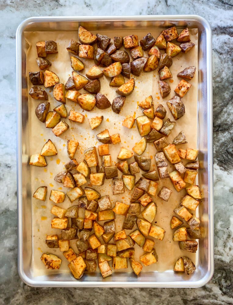 Overhead shot of sheet pan lined with parchment with oven roasted potatoes.