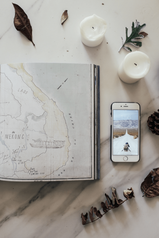 Overhead shot of desk with map of Vietnam, candles, phone, and leaves.