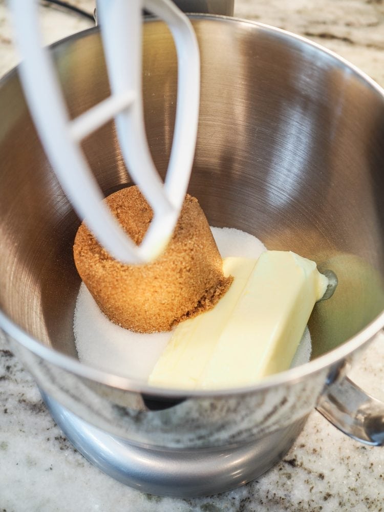 A look inside a stand mixer with brown sugar, regular sugar, and two sticks of softened butter before mixing.