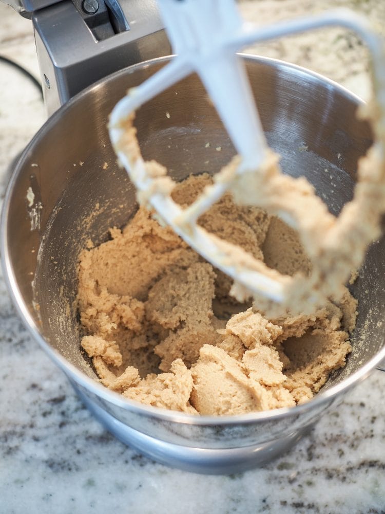 A look inside stand mixer showing butter and sugar mixed and looking a bit more like cookie dough.