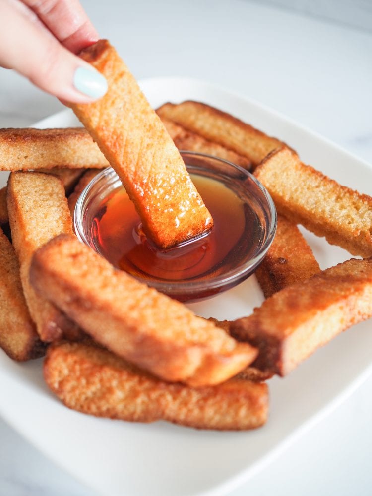 Dipping french toast sticks into syrup.
