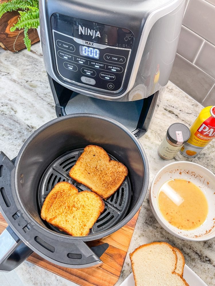 Overhead view inside Ninja air fry basket showing two pieces of air fried French toast, with the batter and dry bread on the side ready to make some more.