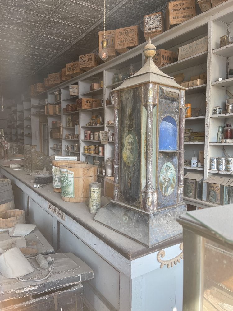 Another view inside the general store showing a coffee display, buckets for sweets, and boxes for sauerkraut and mustard.