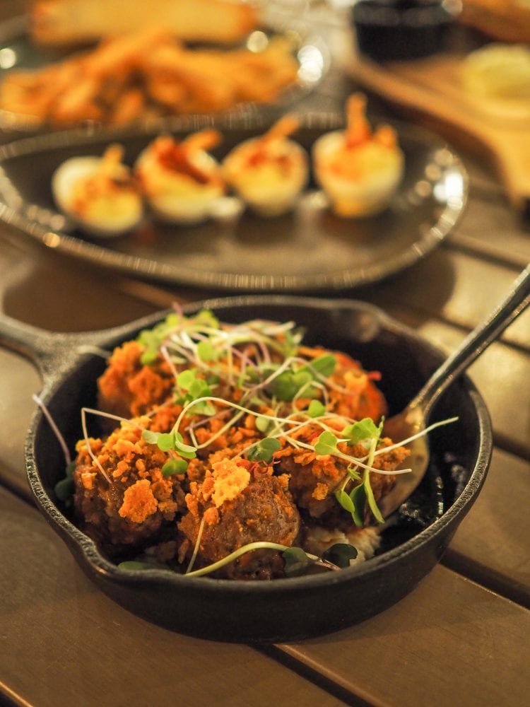 Meatball appetizer in cast iron skillet and topped with micro greens.