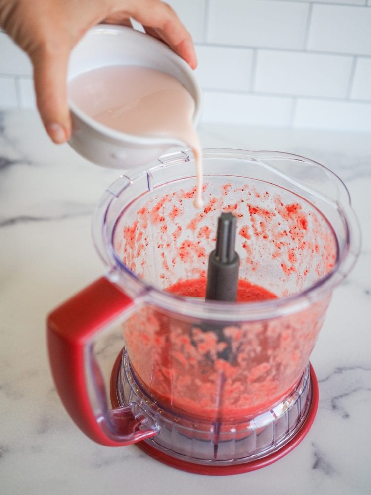 Pouring liqueur into blender with strawberry puree.