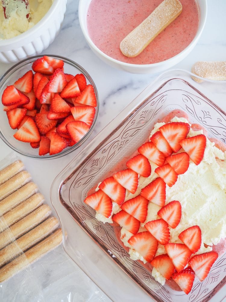 Overhead shot of layering whipped mascarpone cream and strawberries to make strawberry tiramisu.