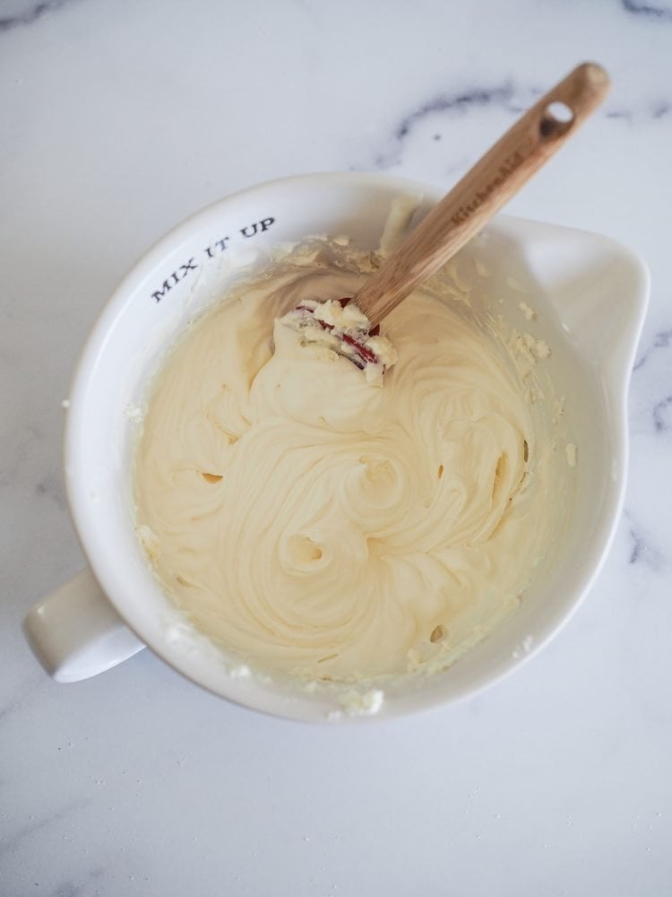 Mixing bowl with whipping cream, mascarpone, and confectioners sugar AFTER blending showing swirling soft peaks.