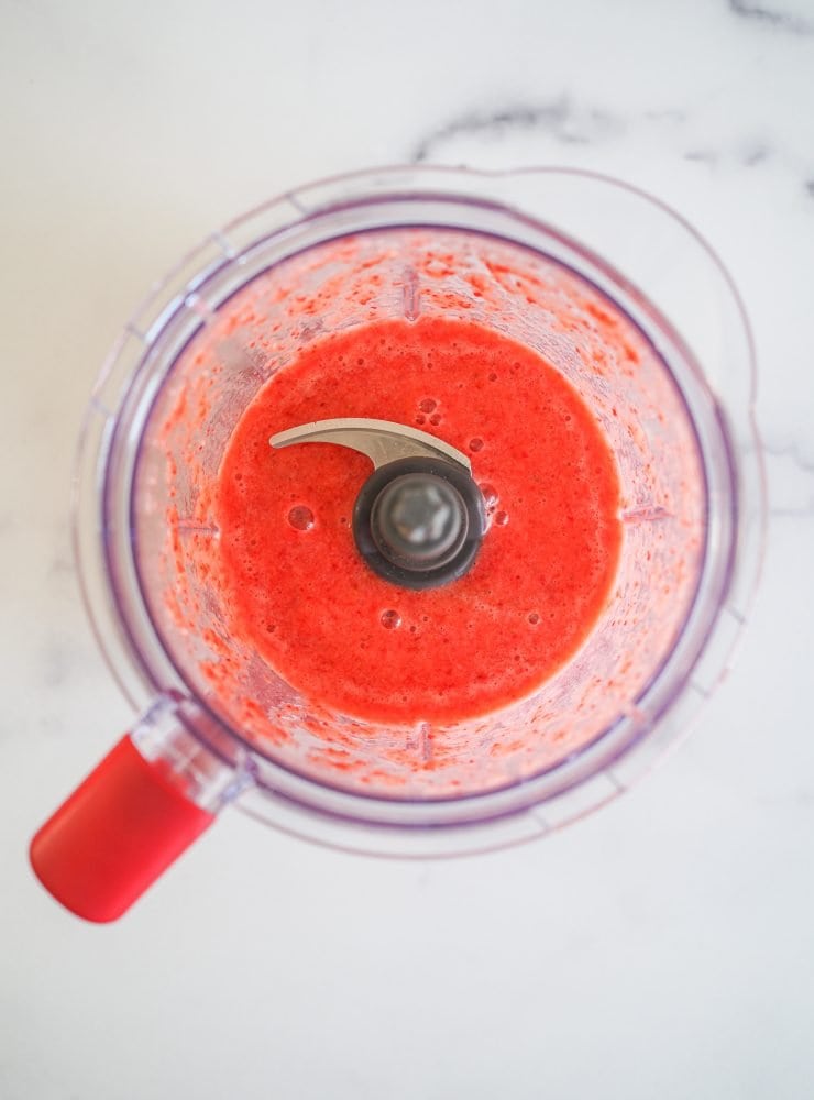 Overhead view of strawberries, lemon juice, and sugar blended in a blender.