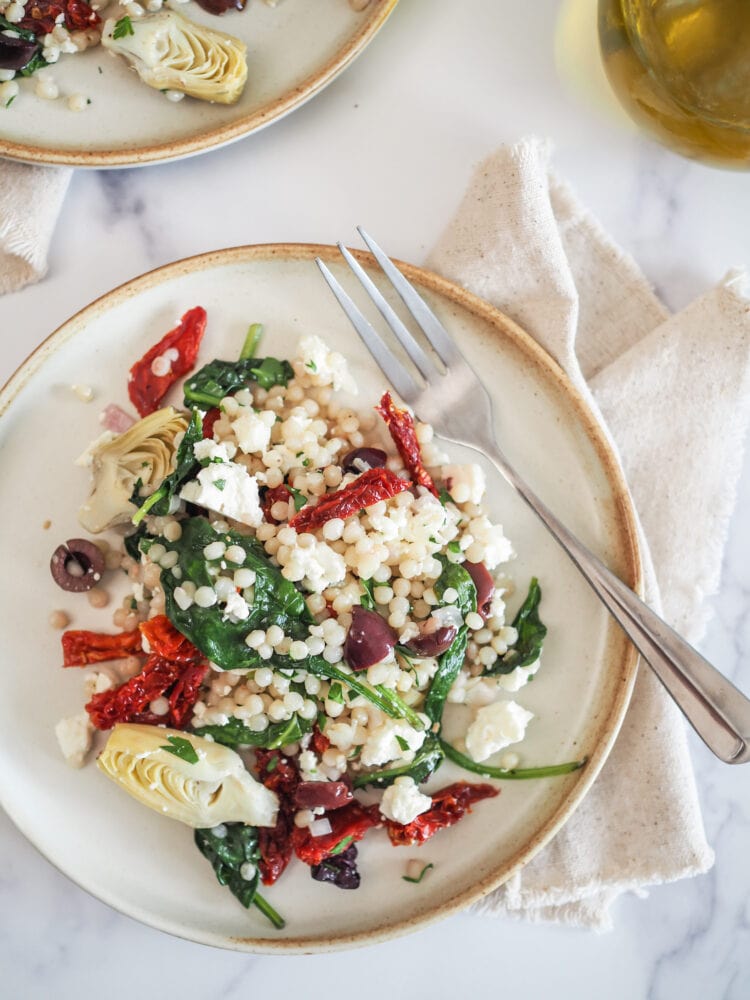 Mediterranean Couscous Salad on plate with fork and napkin to the side.