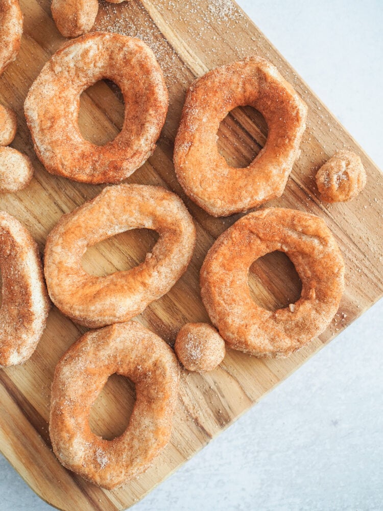 Raw biscuit dough shaped into donuts and dusted in cinnamon sugar.