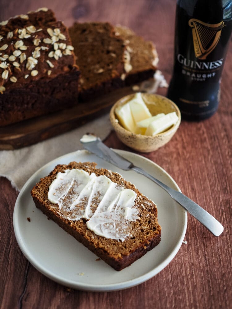 Irish Brown Bread on a plate with a smear of butter, and a Guinness to the side.
