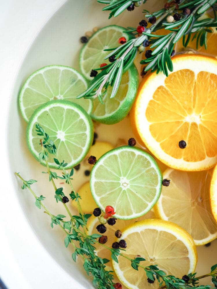 a simmer pot filled with sliced limes, rosemary, sliced oranges, peppercorns, and thyme