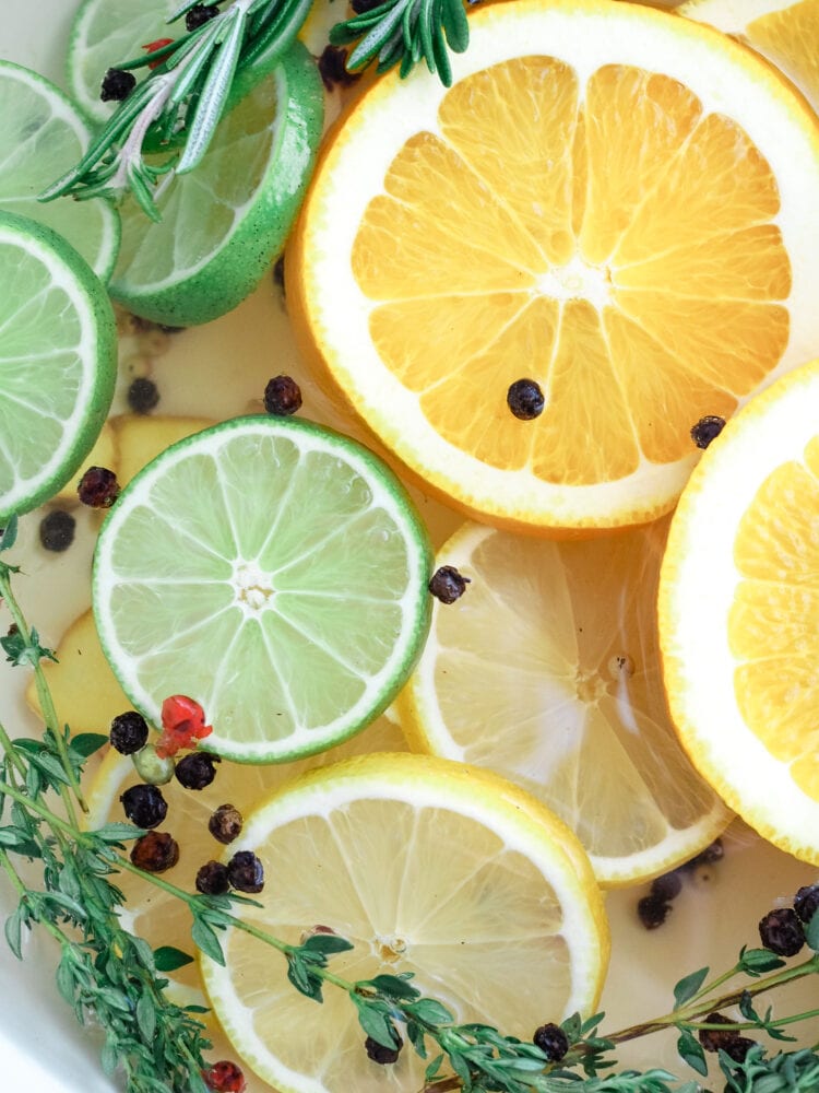 a simmer pot filled with sliced limes, rosemary, sliced oranges, peppercorns, and thyme