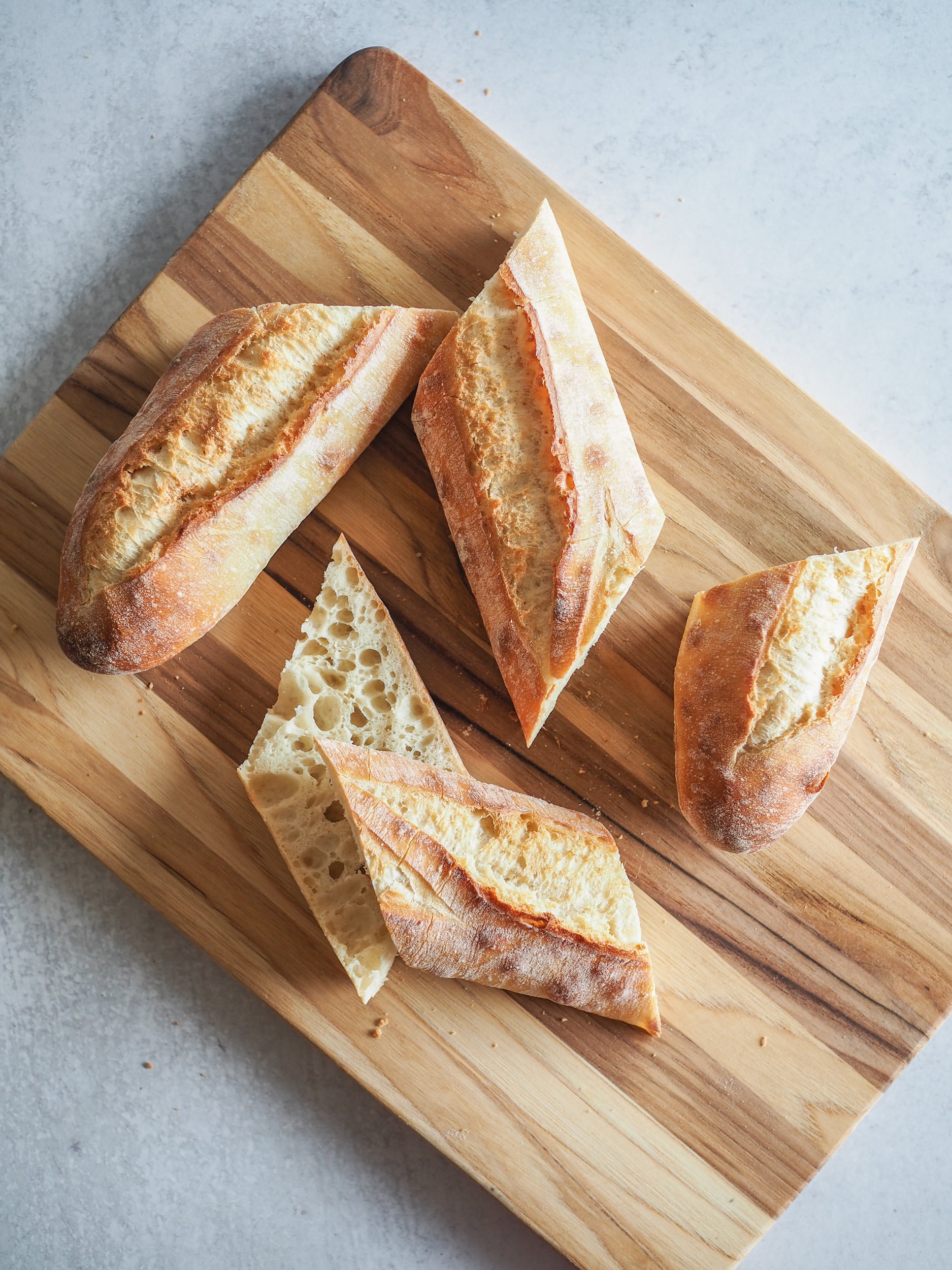 Baguette sliced into four pieces on a cutting board.