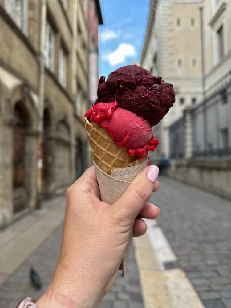 A scoop of raspberry and blueberry glace in a wafflecone.