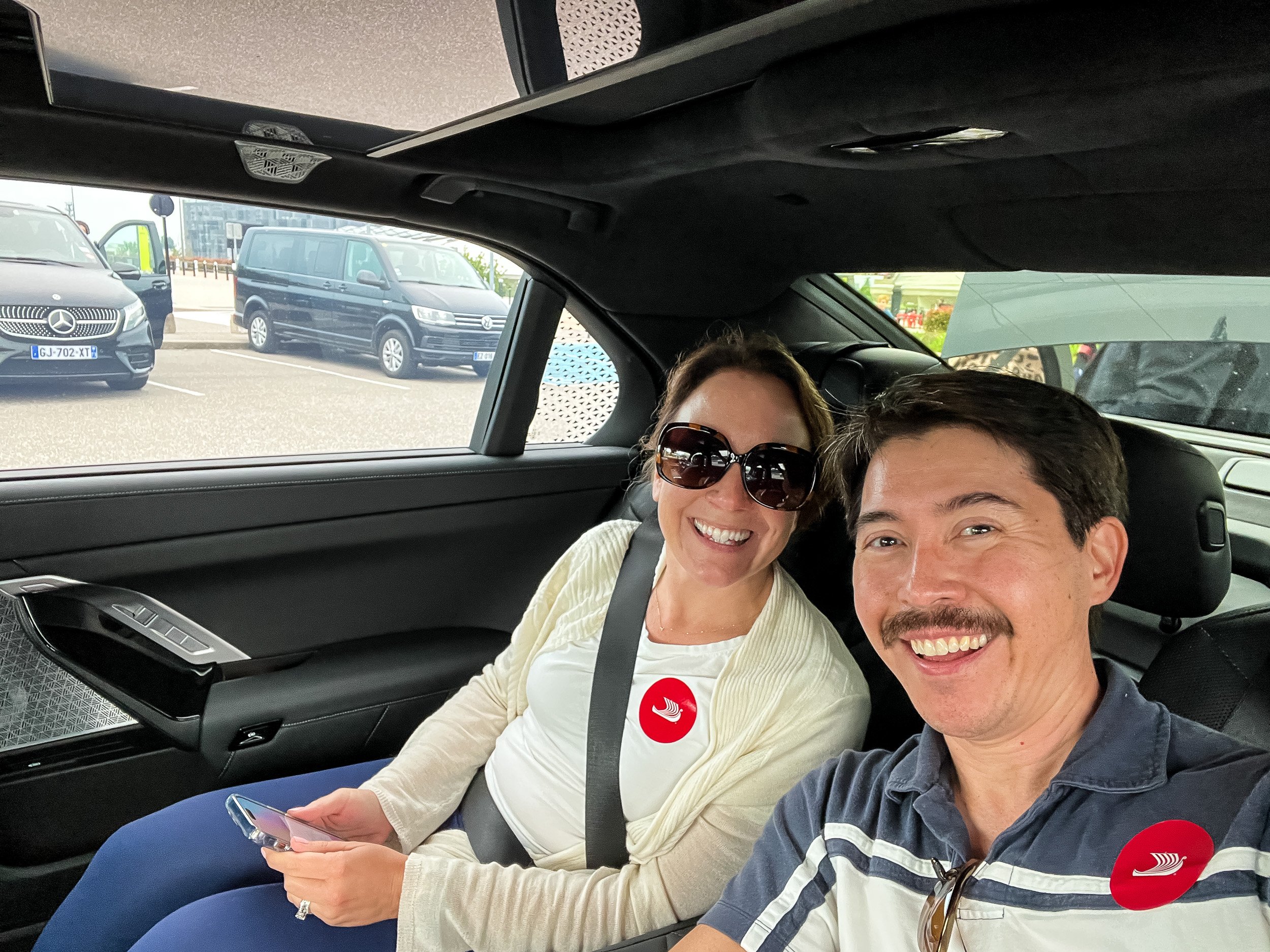Rachelle and Pete, wearing red Viking stickers to identify they're with Viking River Cruises, in the airport pickup vehicle on their way to the ship. 