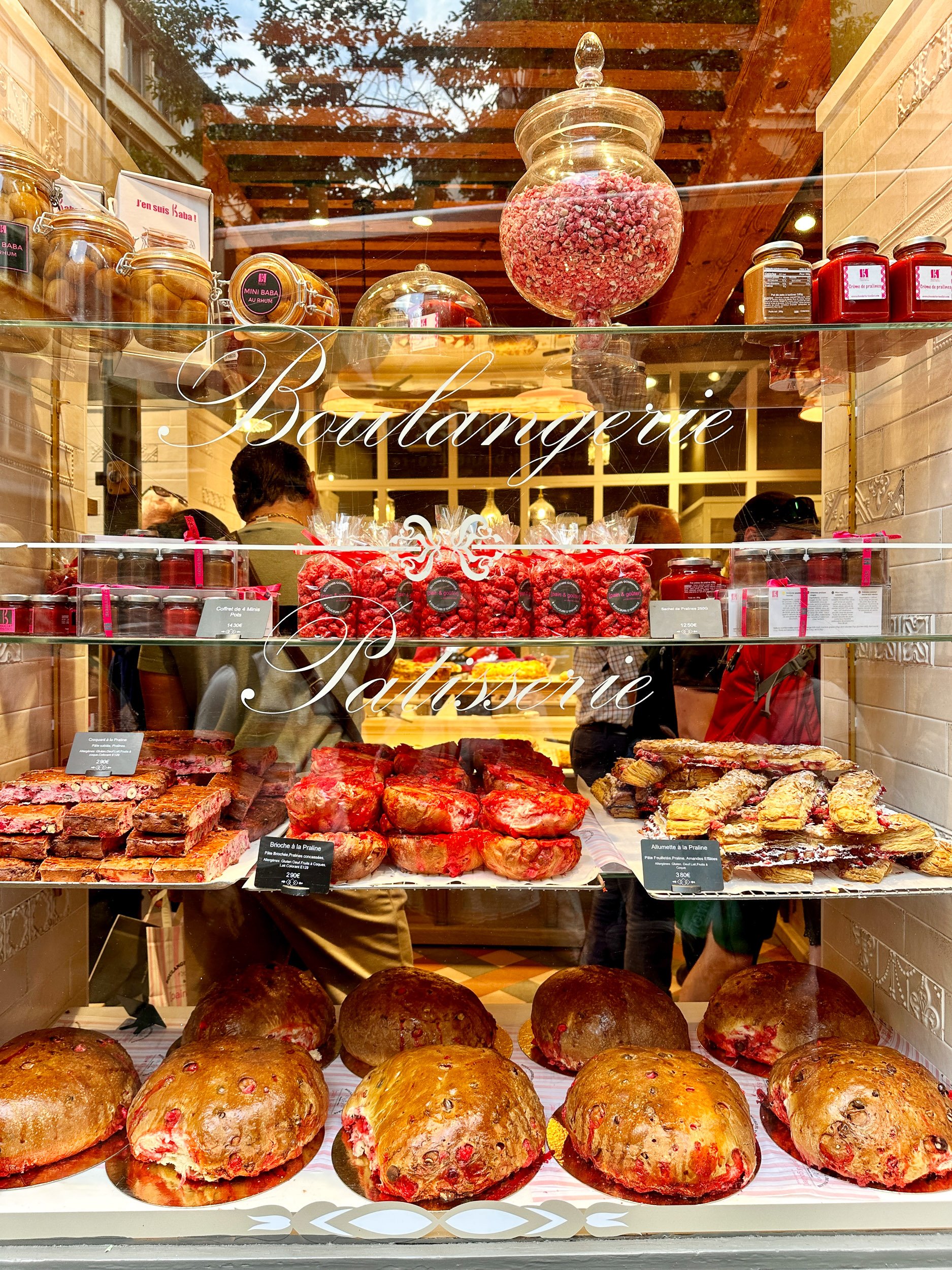 A patisserie window featuring many different pastries including brioches aux pralines roses.