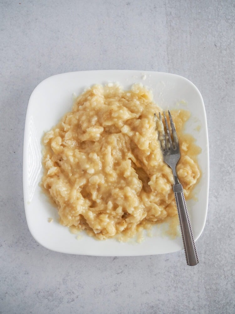 mashed bananas on a white plate with a fork
