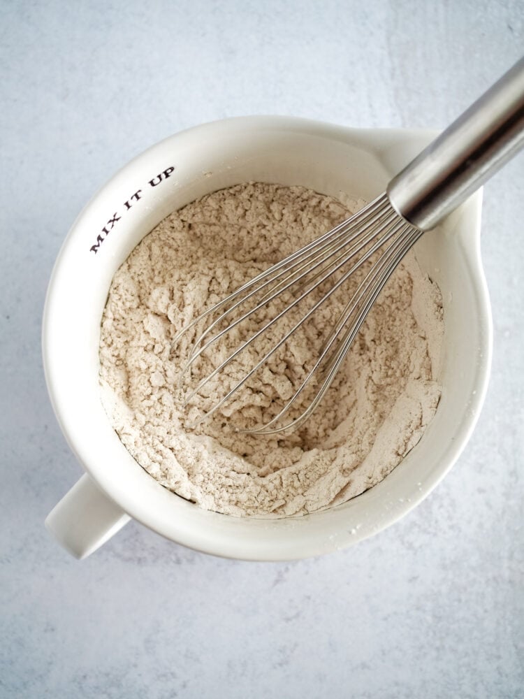 dry ingredients for banana nut muffins whisked together in a small white mixing bowl