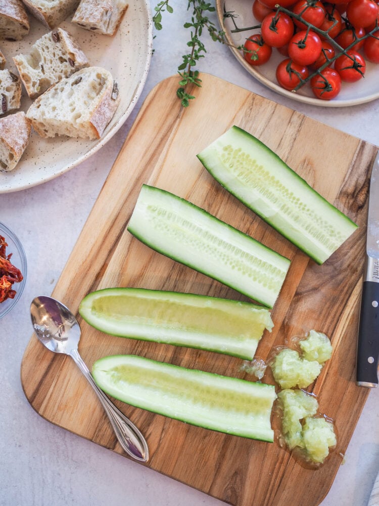 Cucumbers cut in half with the seeds scraped out by a spoon.