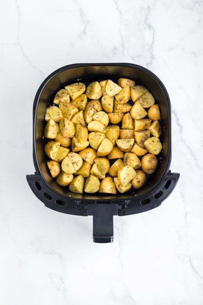 seasoned potatoes, in an square air fryer basket, shown before cooking