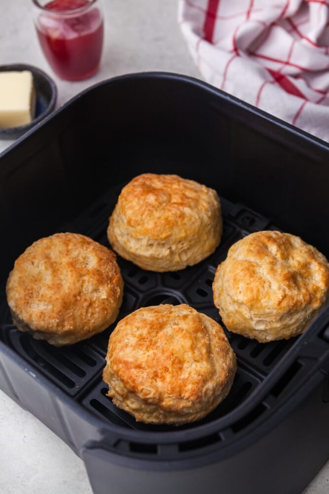 Four golden biscuits in an air fryer basket.
