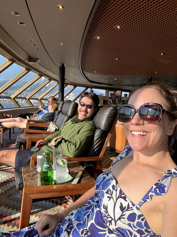 Rachelle and Pete relaxing with a tonic water and taking in the panoramic view in The Crow's Nest on board Holland America cruise ship.