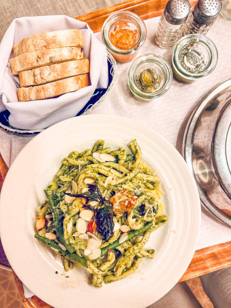 Room service from Canaletto on board Holland America including fresh pasta with pesto, a basket of fresh baked bread, and olives and other condiments in glass Weck jars.