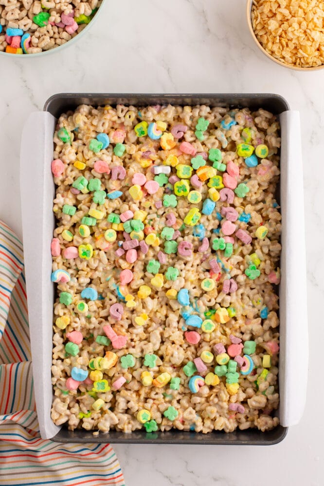 Parchment lined 9x13 pan with lucky charms rice krispie treats pressed into the pan and topped with extra charms marshmallows.