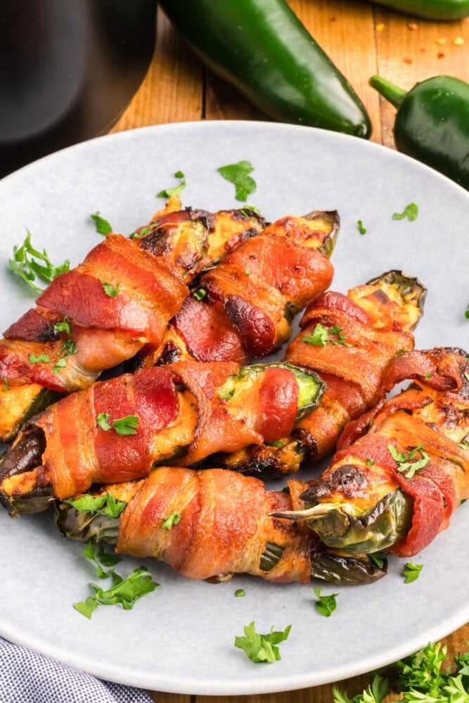 Air fried bacon wrapped jalapeno poppers on a plate.
