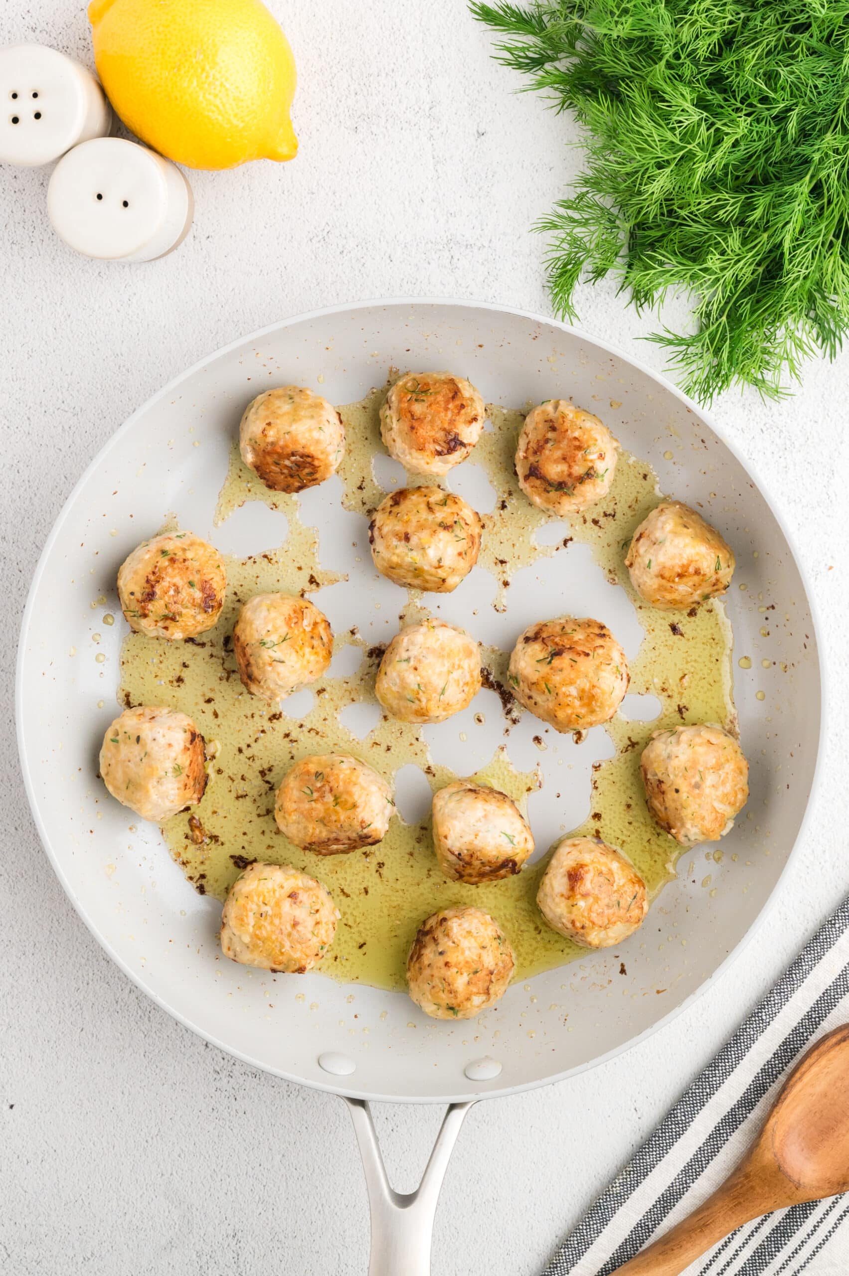 Cooked Greek chicken meatballs in a frying pan, looking golden brown and delcious.