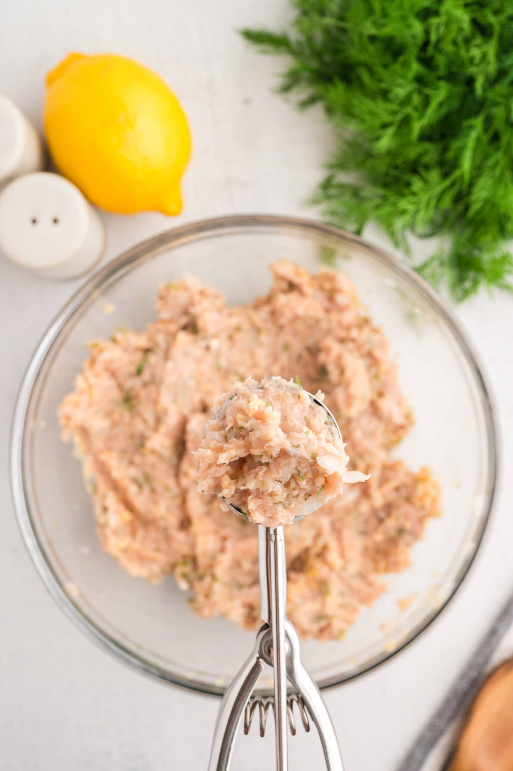 Ground chicken mixed with herbs, spices, and breadcrumbs, scooped in a small cookie scoop to create a meatball.