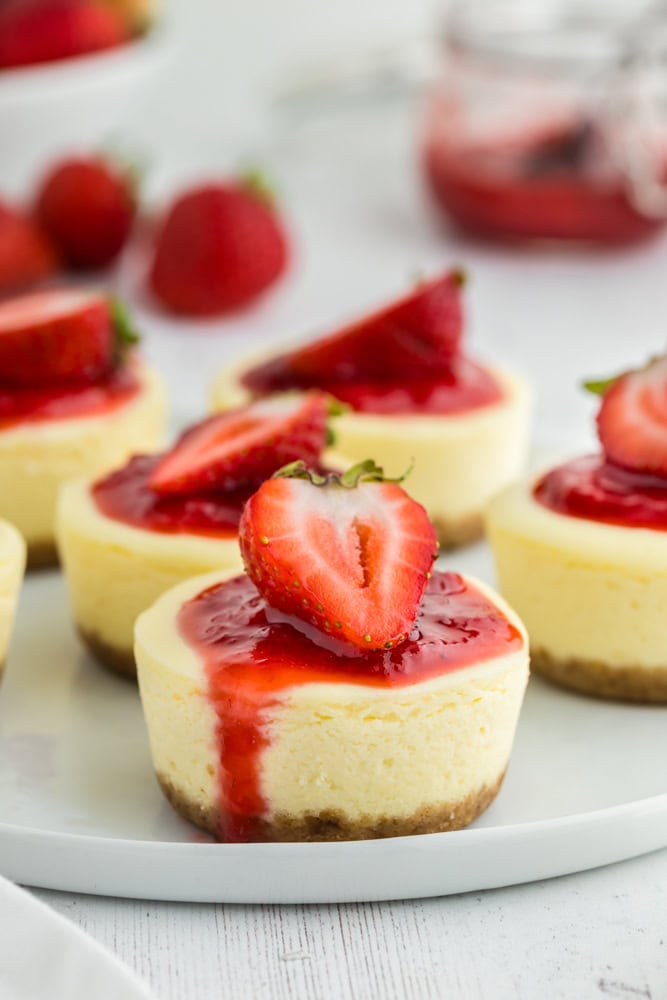 cheesecake bites topped with strawberry on a white serving plate