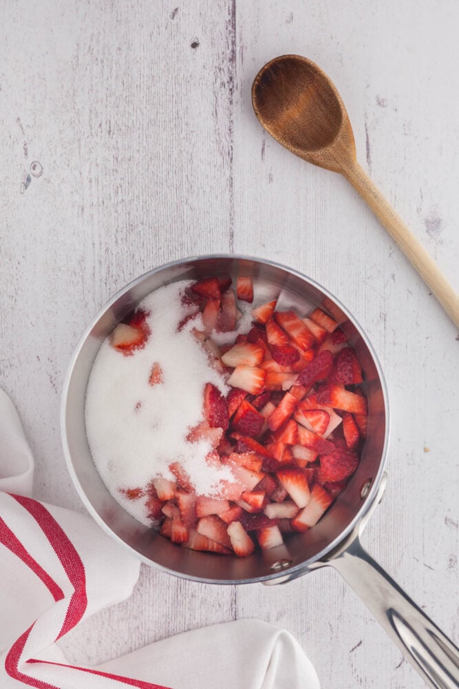 Add finely chopped strawberries and sugar to a saucepan.