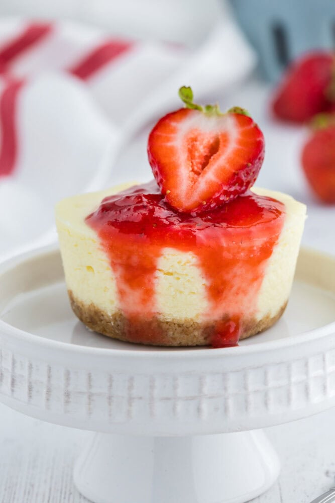 A bite of cheesecake placed on a mini cake stand.