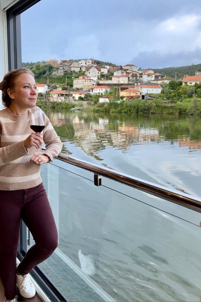 Rachelle sipping wine in an Avalon Waterways panoramic suite overlooking the Douro river.