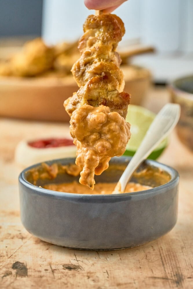 dipping thai chicken satay in peanut sauce