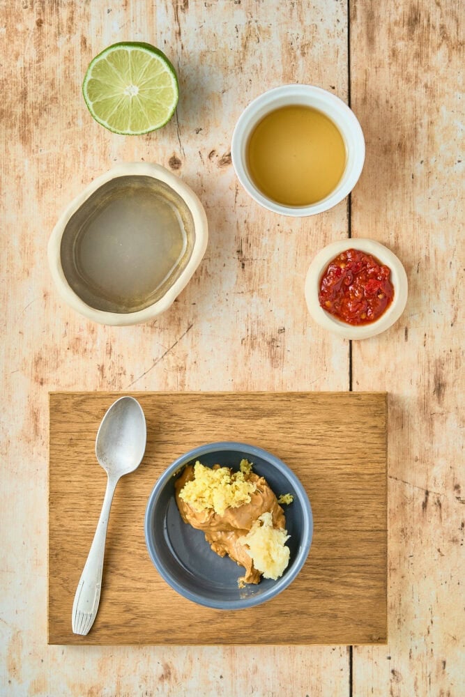 ingredients to make thai peanut sauce including lime, water, honey, peanut butter, ginger, and spices