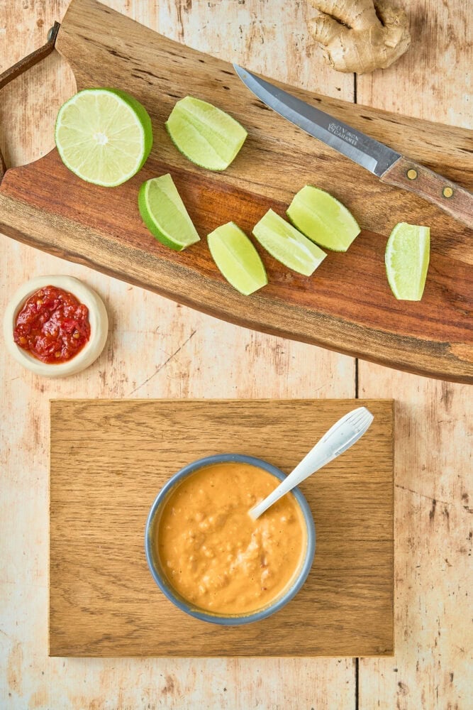 peanut sauce in a bowl and sliced limes on a cutting board