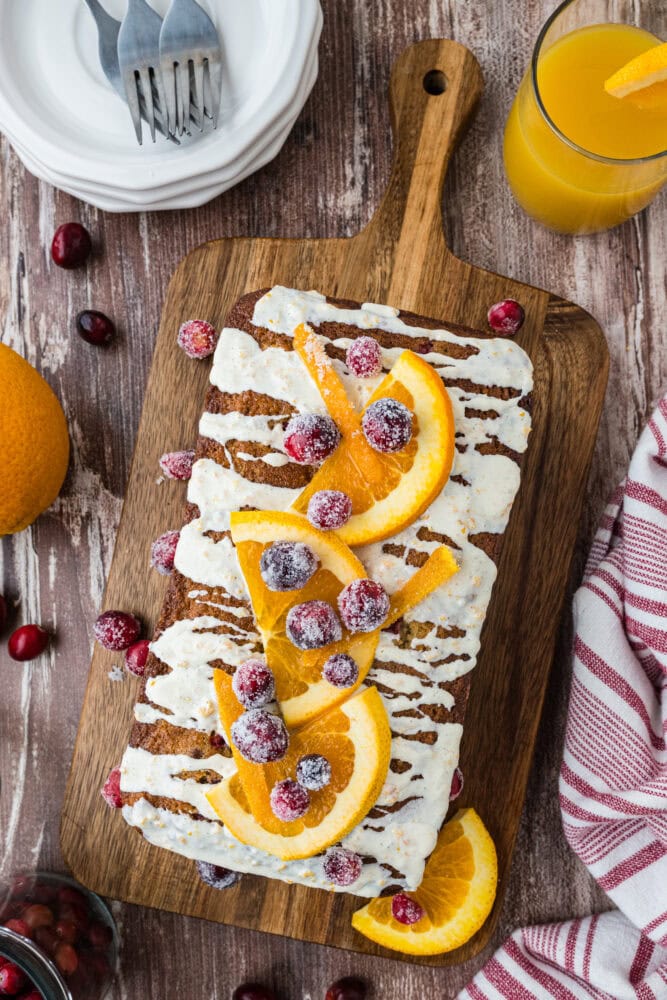 cranberry orange loaf with citrus glaze, garnished with oranges and cranberries