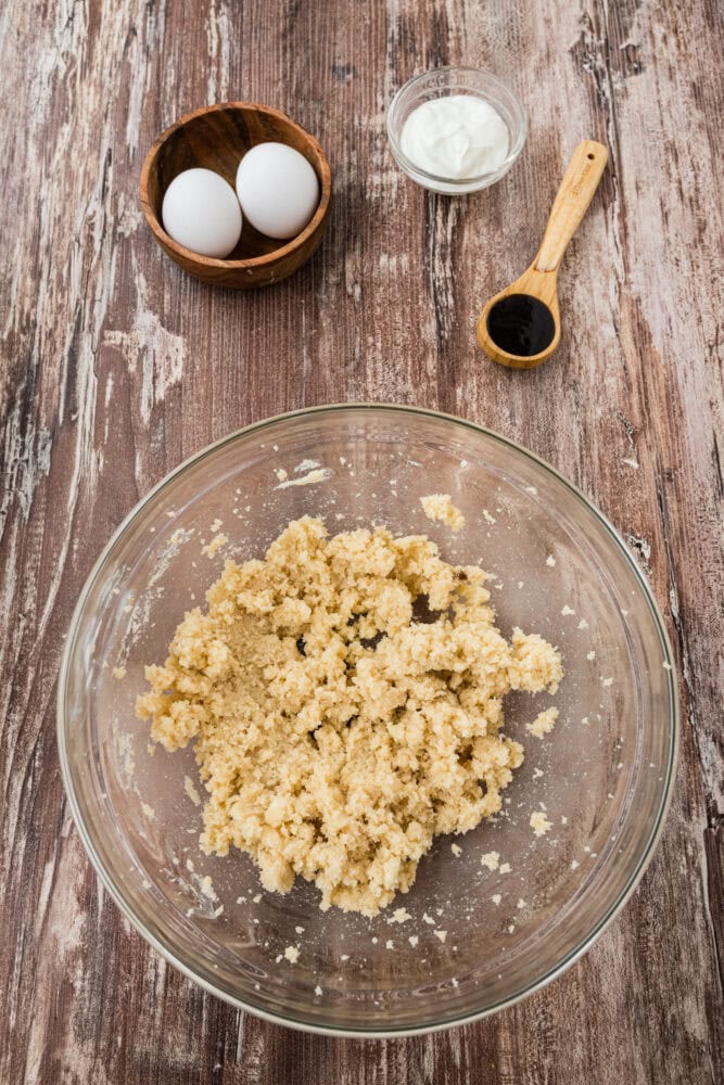 butter and sugar whipped in a bowl, with eggs and other ingredients outside of bowl before adding