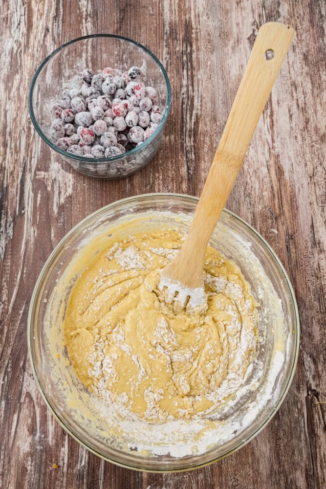 Adding flour coated cranberries to cranberry orange loaf batter