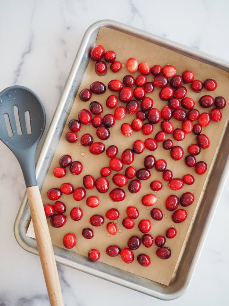 Cranberries coated in simple syrup drying on parchment.