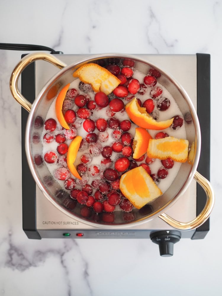 Cranberries, sugar, and orange peel in a saucepan