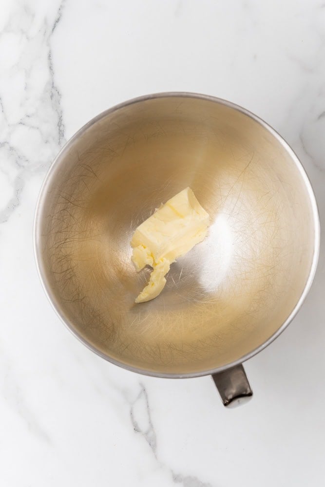 Adding stick of softened butter to stand mixer bowl.