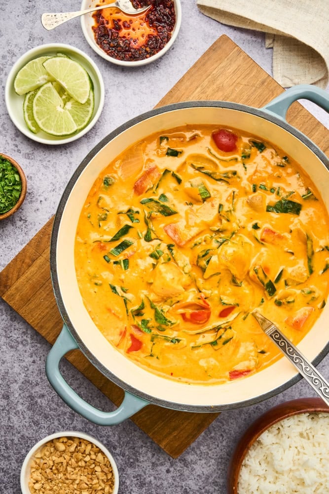 Thai pumpkin curry in enamel cast iron skillet with garnishes on the side