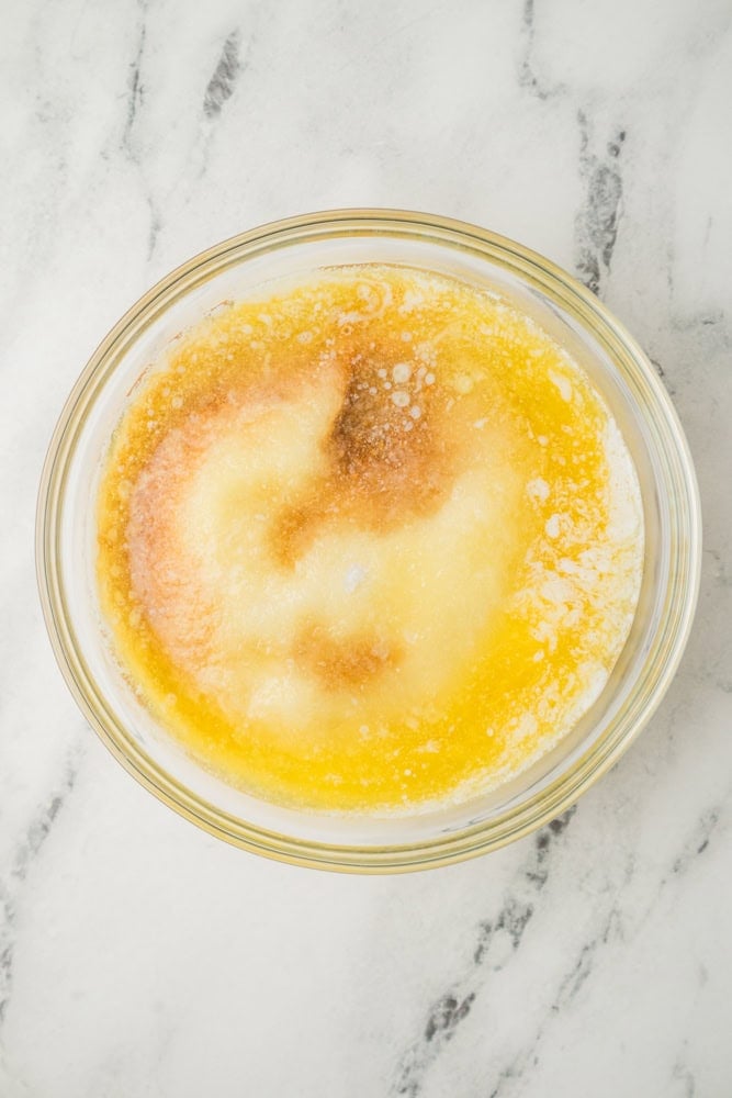 Melted butter added to dry ingredients in a glass bowl