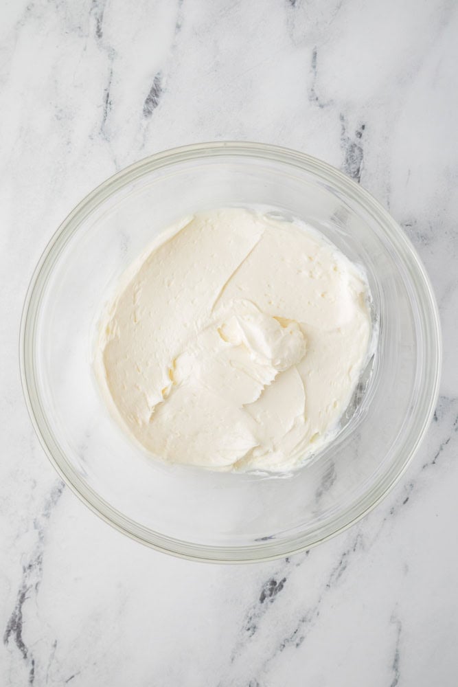 whipped cream cheese and powdered sugar in a glass bowl