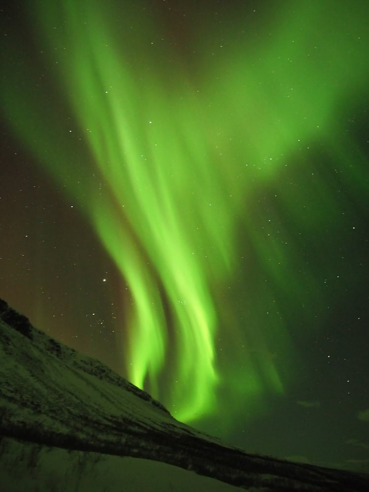 green aurora lights over a mountain