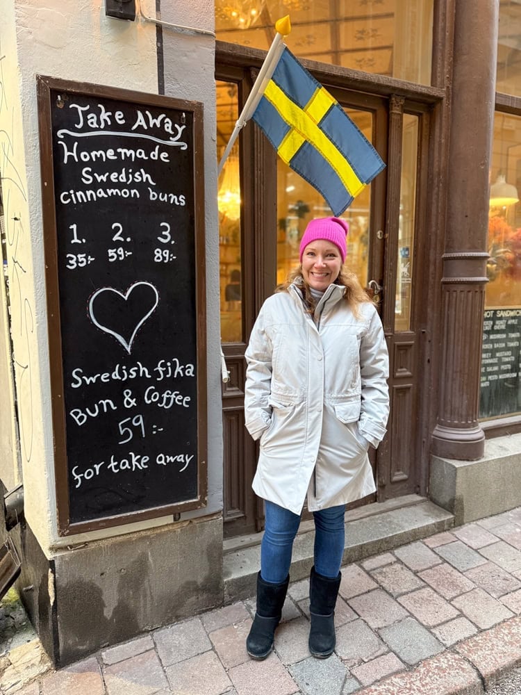 Rachelle outside of a Swedish cafe with the Swedish flag above her
